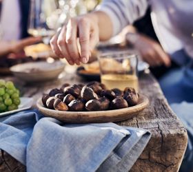 Eine Person greift nach einer Schale mit gerösteten Kastanien