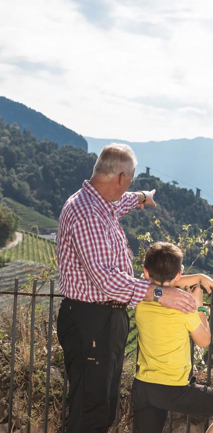 Großvater zeigt seinem Enkel die Aussicht über das Tal und die Stadt Bozen von oben.